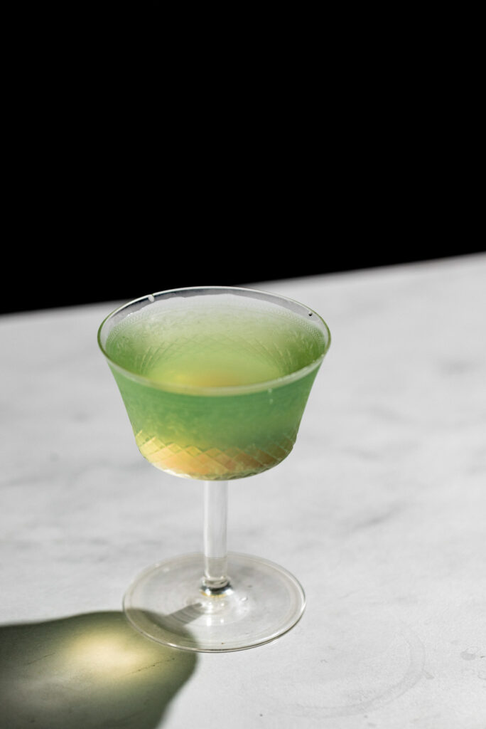 The green last word cocktail strained into a glass.